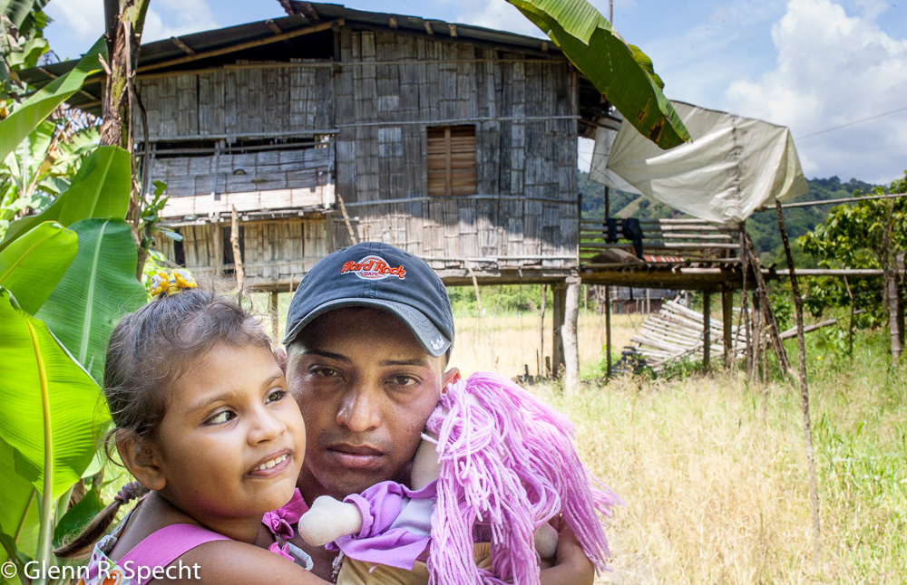 Father carries his blind daughter away from their damaged house in Manabi.